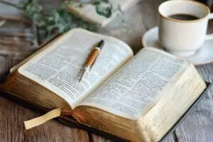 A beautiful Bible journal with handwritten notes and sketches lies open next to a Bible, illustrating a creative and personal study method
