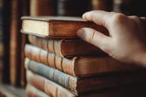 A hand choosing the Gospel of John from a selection of Bible books, representing the best books to start reading