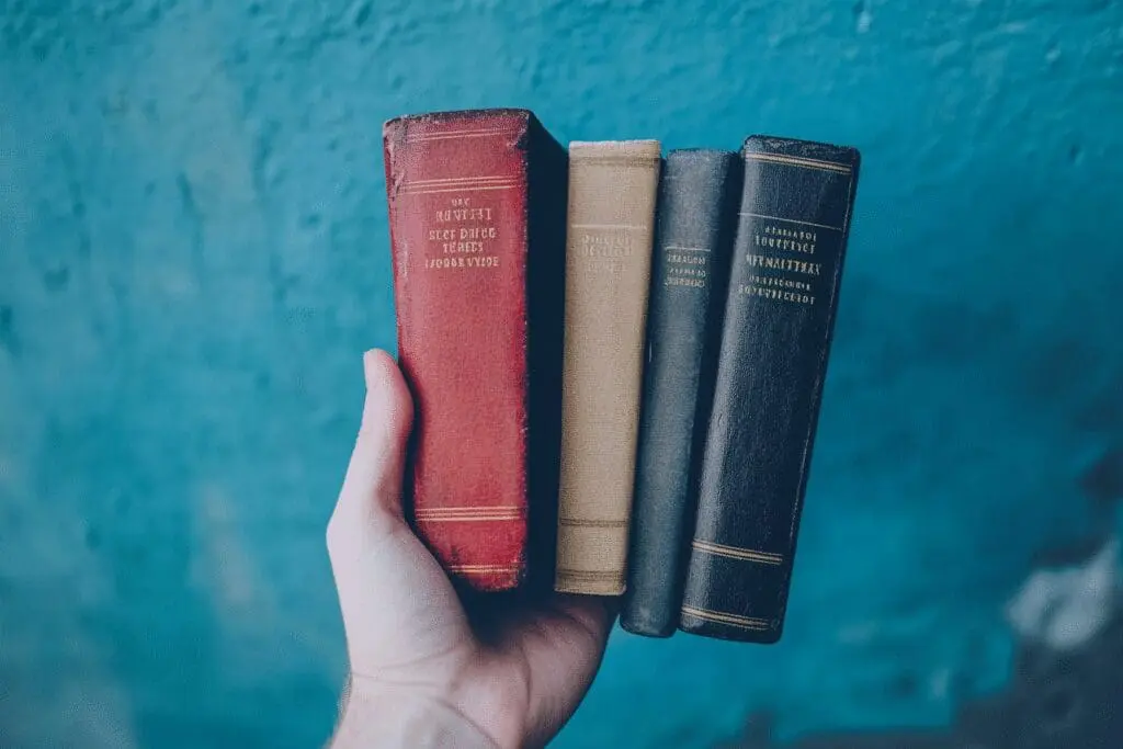 A hand holding up three different Bible versions, showing their varying page counts