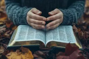 A person praying with their hands on an open Bible, illustrating the powerful method of praying the scriptures