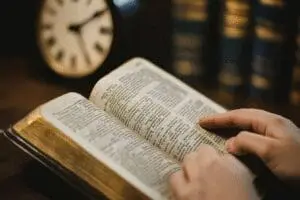 A person reads their Bible peacefully, with a clock in the background, symbolizing the question of how long to read each day