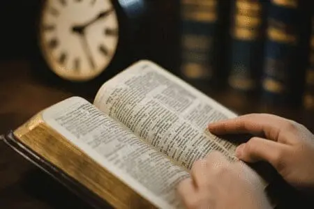 A person reads their Bible peacefully, with a clock in the background, symbolizing the question of how long to read each day