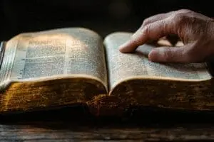 A scholarly hand analyzing an open ESV Bible, symbolizing expert analysis and review of its accuracy