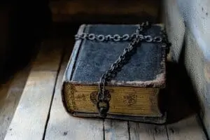 An antique Geneva Bible, symbolically chained in a shadowy setting, with a light revealing why it was banned