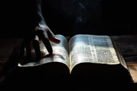 An open Bible with a glowing verse, and a shadowy hand, symbolizing a secret method for quoting verses