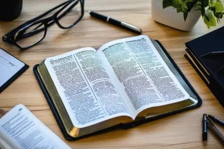 An open NIV Bible on a desk surrounded by scholarly items, representing academic analysis of its accuracy