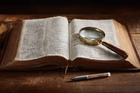 A magnifying glass and highlighter on a study Bible showing an example of what is the best study Bible