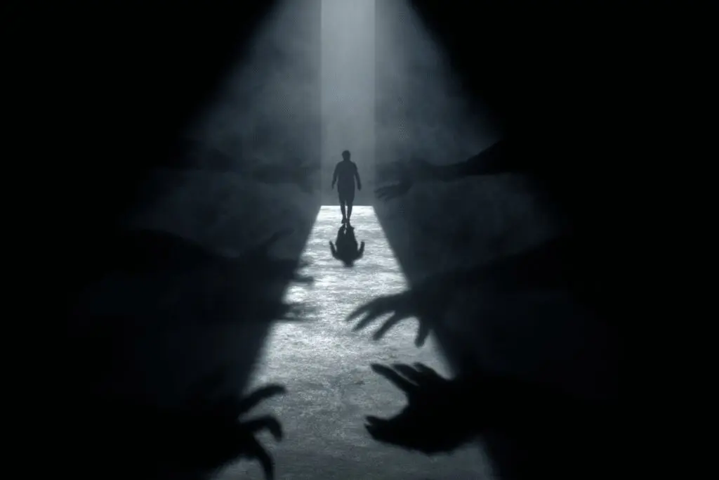 A person overcoming shadowy hands to stay on a path of light illustrating what is temptation in the Bible