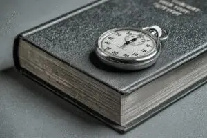 A stopwatch placed beside a Bible representing the answer to how many hours to read the Bible