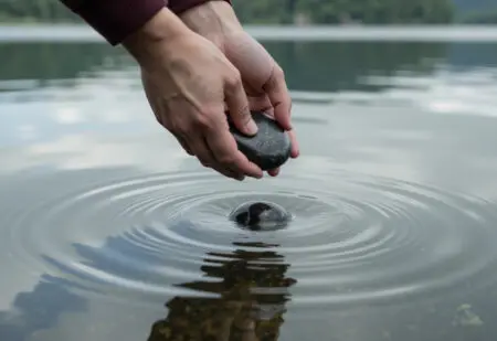 a persons hands releasing a heavy stone into water representing what the bible says about forgiveness and letting go