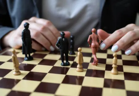 an image of a person playing chess with living people symbolizing the controlling nature of manipulation