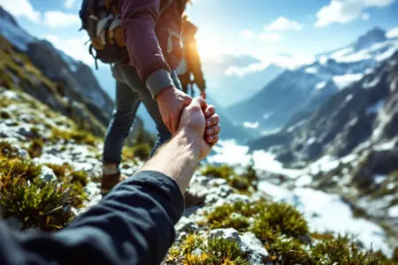 one person pulling another to safety on a hiking trail symbolizing what the bible says about trusting others in a supportive community